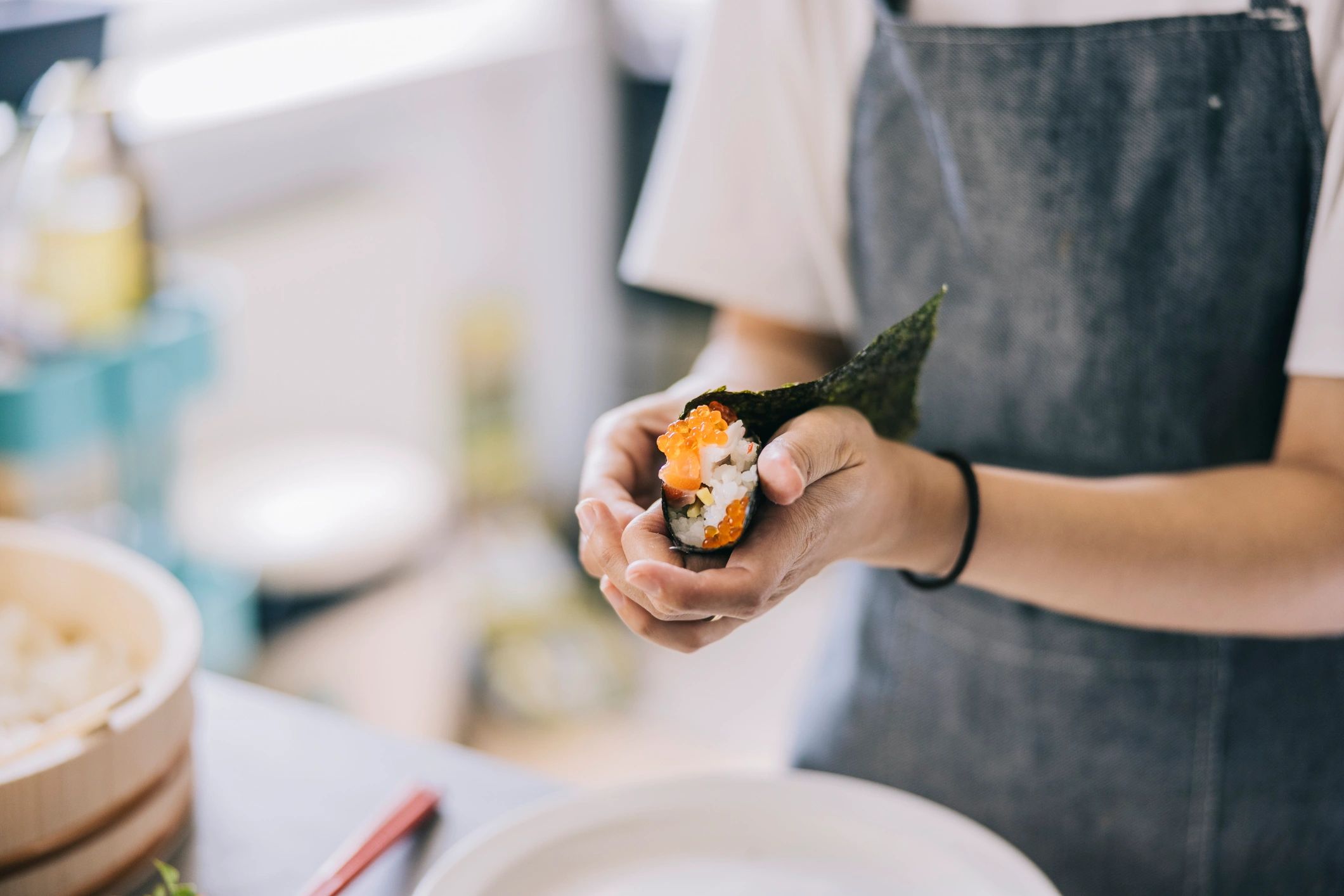 Hands preparing fresh sushi rolls